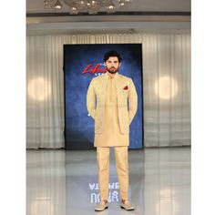 a man standing in front of a chandelier wearing a yellow suit and tie