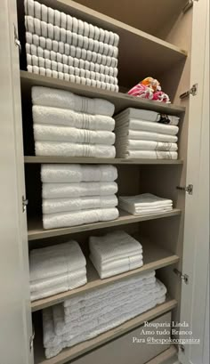 the closet is full of folded towels and other white linens in it's shelves