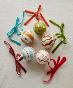 six decorated easter eggs tied with ribbons on a white tablecloth, all in different designs and colors