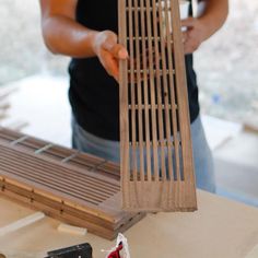 a man is working on a wooden structure with wood slats attached to the sides