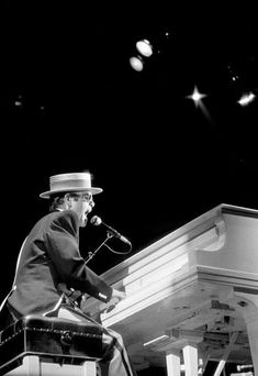 a man sitting on top of a piano in front of a microphone