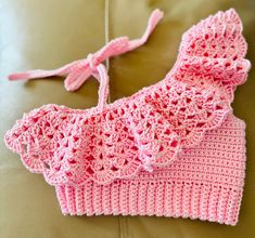 a pink crocheted hat sitting on top of a couch next to a pillow