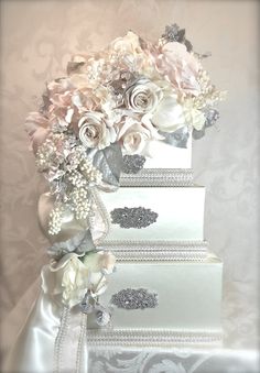 three tiered wedding cake decorated with flowers and pearls