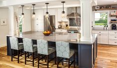 a large kitchen with an island in the middle and four chairs at the counter top