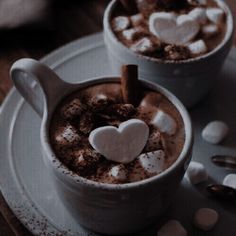 two cups filled with hot chocolate and marshmallows on top of a table