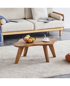 a coffee table with fruit on it in the middle of a living room area next to a couch