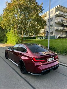 a red sports car parked on the side of the road in front of an apartment building