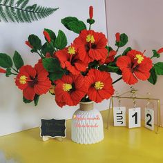 a vase filled with red flowers sitting on top of a yellow table next to a sign