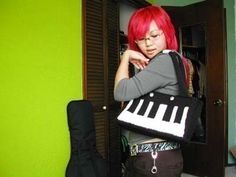 a woman with red hair is standing in front of a guitar case and looking at the camera