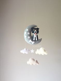 a mobile made to look like a cat sitting on the moon with clouds hanging from it