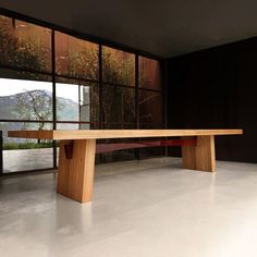 a long wooden table sitting in front of a large window on top of a white floor