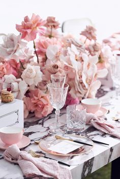 the table is set with pink flowers and place settings for two people to sit at