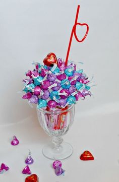 a vase filled with lots of candy sitting on top of a white table next to hearts