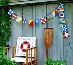 a chair sitting in front of a wooden fence with flags on it and a shovel