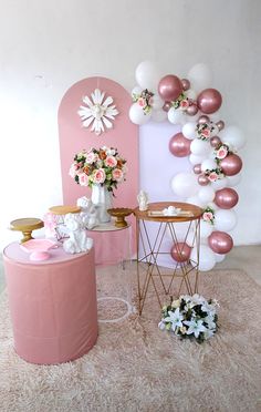 a pink and white party setup with balloons, flowers, and other decorations on the floor