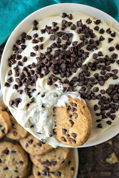 a bowl filled with cookies and cream next to chocolate chip cookies on a blue towel