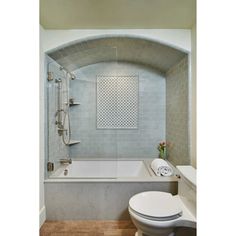 a white toilet sitting next to a bath tub under a bathroom window above a sink