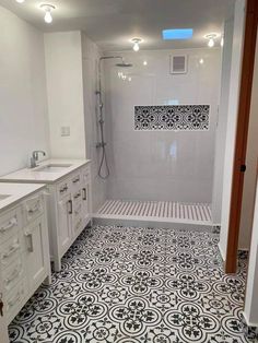 a white bathroom with black and white tile flooring on the shower wall, sink, and toilet