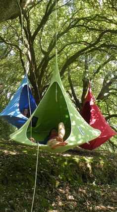 two people are sitting in tents hanging from trees