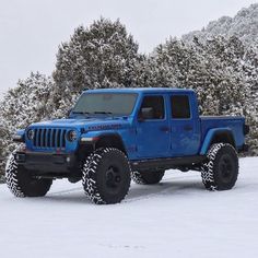 a blue jeep is parked in the snow