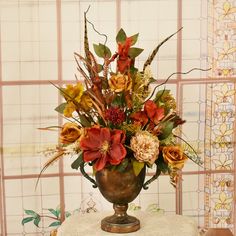 a vase filled with lots of flowers sitting on top of a table next to a wall