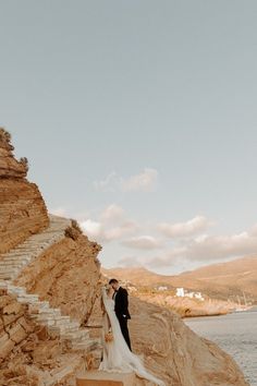 a bride and groom standing on the edge of a cliff