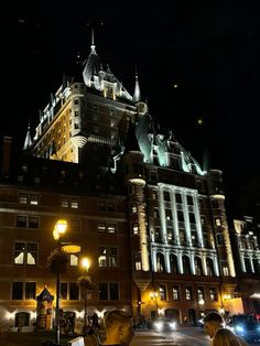 two men are sitting outside at night in front of a large building with many windows