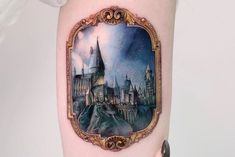 a woman's thigh with a hogwarts castle tattoo on it and a frame around her leg