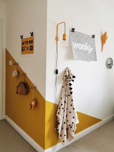 a yellow and white room with polka dot towels hanging on the wall next to a coat rack