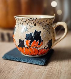 a coffee cup decorated with black cats and pumpkins