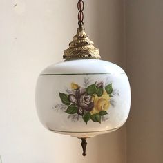 a hanging light with flowers painted on it