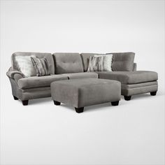 a gray couch and ottoman with pillows on it