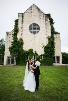 a bride and groom standing in front of an old church