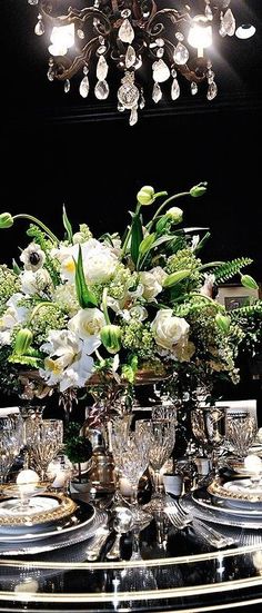 a dining room table set with silverware and flowers in a centerpiece on it