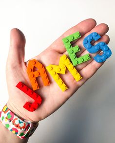 a hand holding up lego letters that spell out the word mom