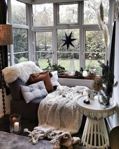 a living room filled with furniture next to a large window covered in blankets and pillows