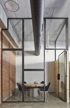 an office with brick walls and glass partitions to divide the room from the dining area