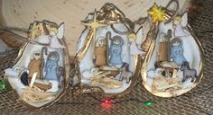 three nativity scene figurines sitting on top of a table next to christmas lights