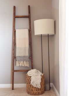 a ladder leaning up against a wall next to a basket with a blanket on it