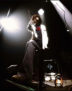 a woman sitting on top of a chair in front of a light