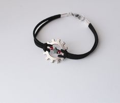 a black cord bracelet with silver gears and red beads