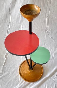 three round tables on top of each other in different colors and sizes, sitting on a white sheet