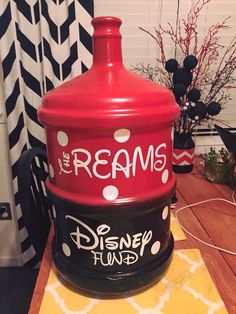 a large red jug sitting on top of a wooden table next to a black and white wall