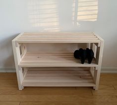 a pair of black shoes sitting on top of a wooden shelf next to a wall