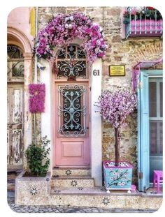 an old building with pink flowers on the front door