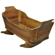 an old wooden baby cradle with no wheels on it's legs and the seat is made out of wood