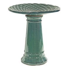 a green pedestal with an intricate design on the top and bottom, sitting in front of a white background