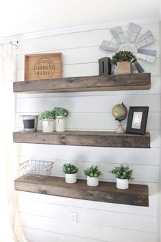 three wooden shelves with potted plants on them in front of a white shipboard wall