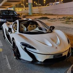 a white sports car parked next to a black car