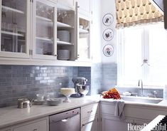 a kitchen filled with lots of white cabinets and counter top space next to a window